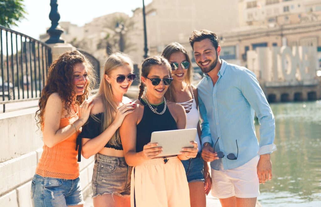 A group of friends laughing while looking at something on a tablet